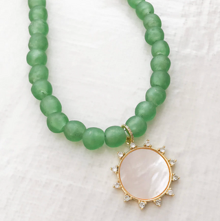 Green beaded necklace with a gold and white pendant