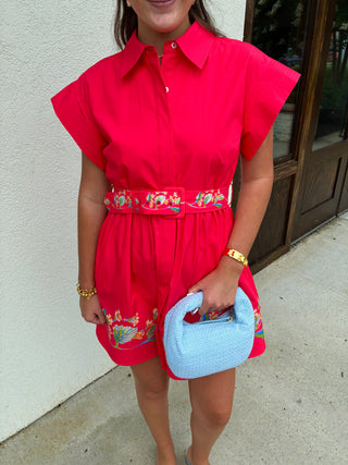 Bright coral dress that has a floral print lining the bottom and belt