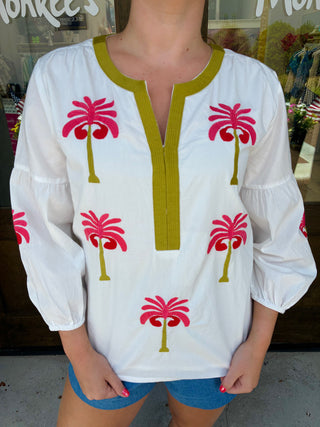 White long sleeve blouse with pink palm tree embroidery and green trim.